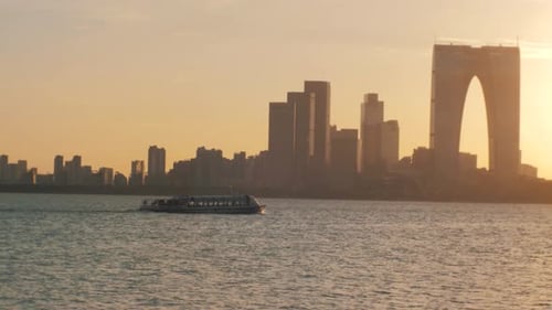 Zeitlupenaufnahme von Sportbootsegeln auf dem See bei Sonnenuntergang, Stadtbild im Hintergrund