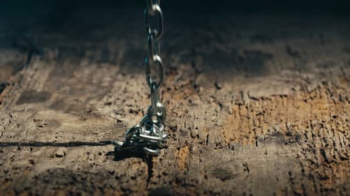 Metal Chain Falls Onto Wooden Surface