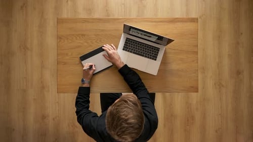 Overhead View of Young Adult Using Tablet and Laptop