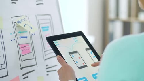 Person Designs Mobile App on Tablet
