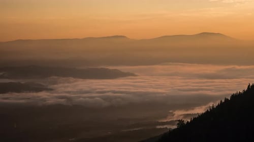 Zeitraffer eines nebligen Tals bei Sonnenuntergang