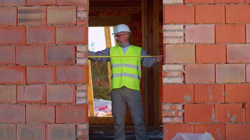 Engineer Architect Conducting Measurements with a Tape Measure on Construction Site of House