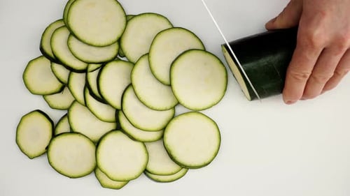 Slicing Green Zucchini on a White Cutting Board