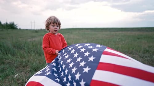 Boy Holding American Flag in Green Field