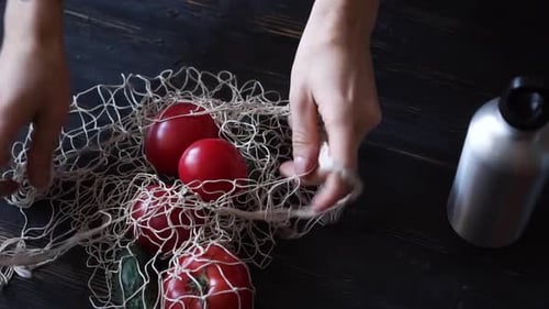 Reusable Grocery Bags with Fruits and Vegetables Reusable Water Bottle on the Kitchen on Black