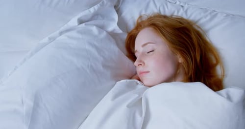 Red-haired Woman Sleeping Peacefully in White Bed