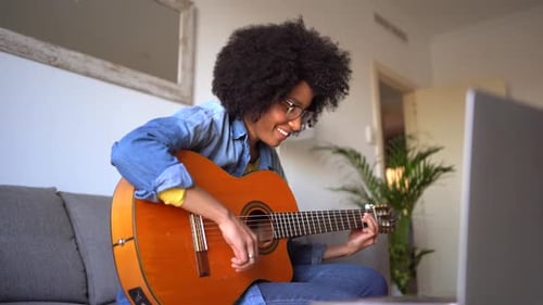 Woman Playing Acoustic Guitar at Home on Couch