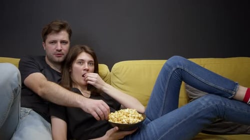 Couple Watching TV and Eating Popcorn Together