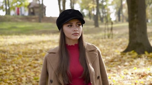 Young Girl in Stylish Clothes Looking Aside with a Smile in Sunny Autumn Park
