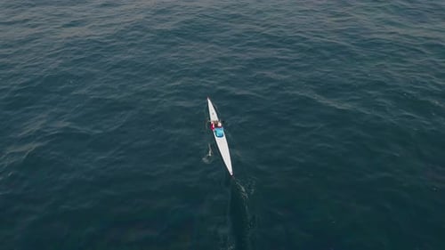 Aerial view above of a man paddling kayak in the sea.