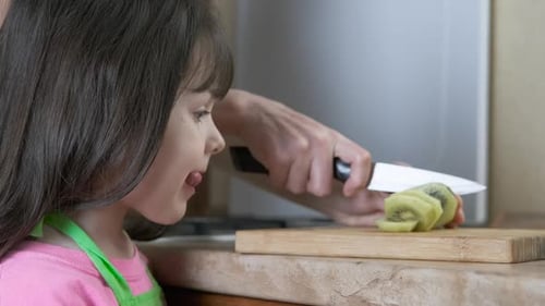 Child Watching Kiwi Being Cut on Cutting Board
