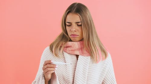 Woman Checking Thermometer on Pink Background
