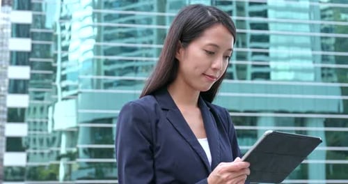 Woman Using Tablet Near Glass Building