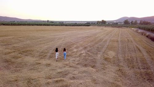 Aerial view two girls walking in the country at sunset