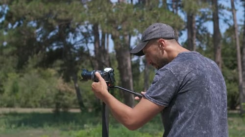 Man Setting Up Camera on Tripod in Woods