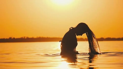 Silhouette d'une femme retournant ses cheveux longs dans l'eau. 240 images par seconde au Ralenti