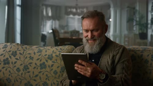 Senior Man Using Tablet on Ornate Couch