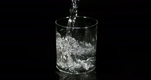 Water being poured into Glass against Black Background, Slow Motion 4K