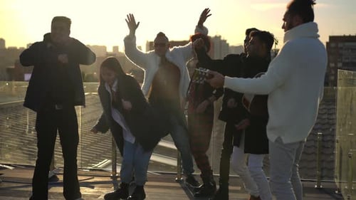 Group of Cheerful Multiethnic People Dancing at Sunset on Rooftop in Urban City