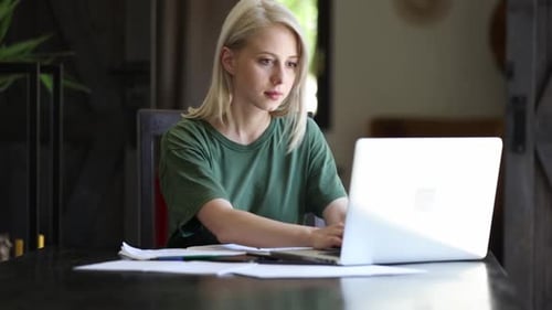 Blonde girl working with notebook at home as freelancer