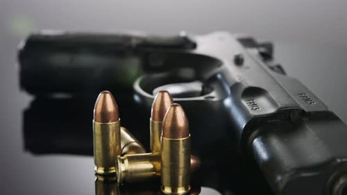Gun Control. 9-mm-Handfeuerwaffe mit Kugeln, die sich auf einer reflektierenden Oberfläche drehen