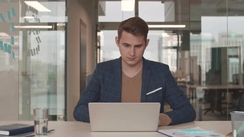 Young Man Working on Laptop in Modern Office