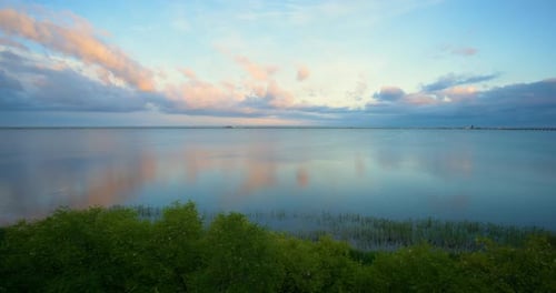 Wunderschöner Sommersonnenuntergang, der sich von der ruhigen Meeresoberfläche in Panorama-