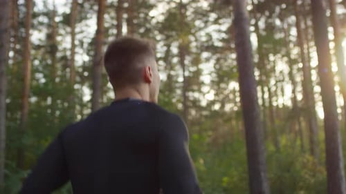 Rear View of Male Athlete Jogging in Woods in the Morning
