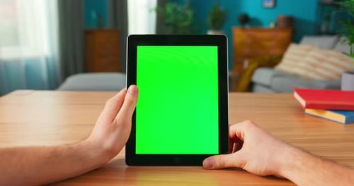Closeup of Man Using Green Mockup Screen Digital Tablet Computer in Portrait Mode While Sitting