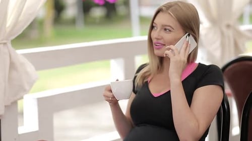 Beautiful girl with light hair wearing colorful shirt sitting in cafe with tablet