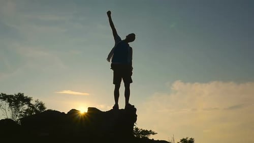 Triumphant Man Silhouetted on Mountain Top at Sunrise