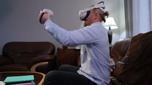 Side View Caucasian Man Gaming Online in Augmented Reality Sitting on Couch in Living Room