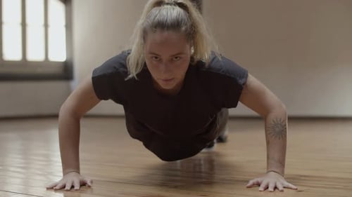 Front View of Focused Caucasian Woman Doing Pushups in Gym