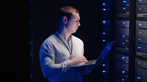 Young Adult Working on Laptop in Server Room