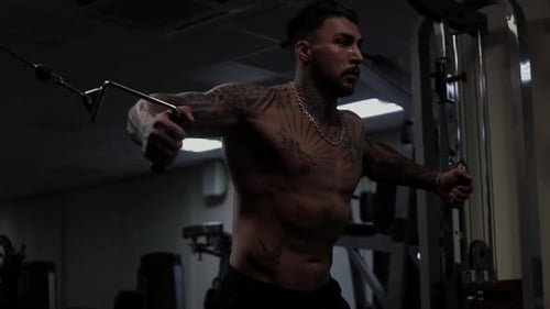 Tattooed Man Working Out on Cable Machine in Gym
