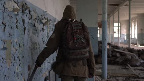 Ein Stalker in einem verlassenen Gebäude fährt mit einem Messer an der Wand entlang