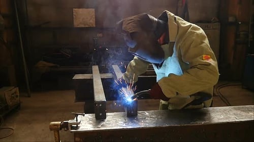 Welder Welding Metal in Dark Workplace