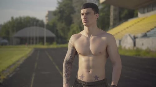 Muscular Man Drinking Water on Running Track