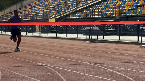 L'athlète termine la course en premier et coupe le ruban rouge, célébrant la victoire