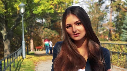 Young Beautiful Woman Smiles To Camera in the Park in Autumn Day