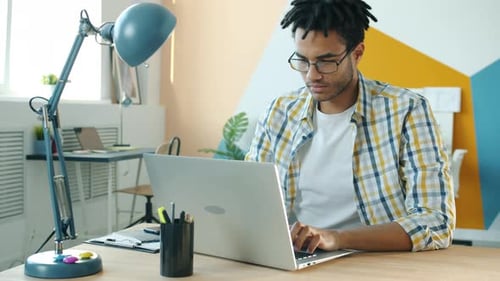 Young Adult Working on Laptop in Creative Office