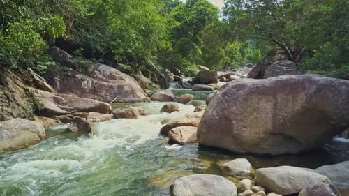 Flycam montre une rivière mousseuse tourbillonnant entre de gros rochers