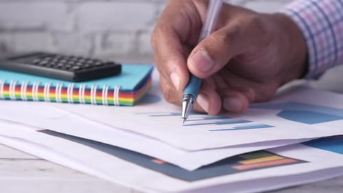 Menschenhand mit Stift Analysieren von Balkendiagramm auf Papier