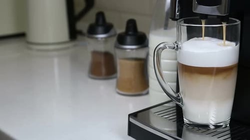 Latte Being Poured into Clear Glass Mug