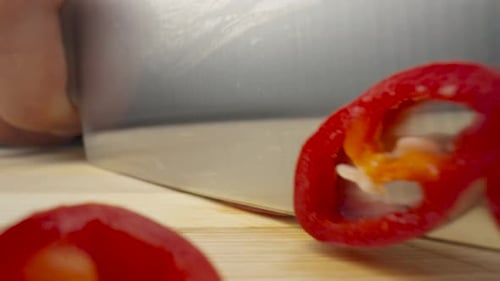 Male Hands Slicing Red Hot Chili Pepper with Sharp Knife on Black Background