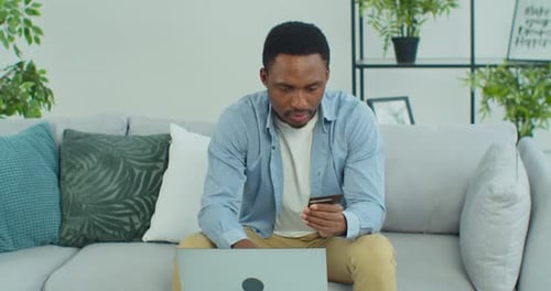 Man Using Credit Card with Laptop on Sofa