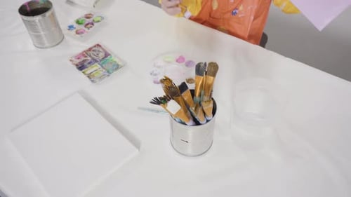 Little girl painting with acrylic paint on canvas with her mother for a distant learning art project