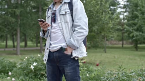 Young Adult on Skateboard Using Phone in Park