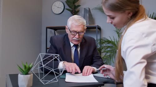 Senior Businessman Company Director Explaining Documents Discussing Project with Woman Colleague