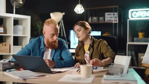 Young Female and Male Professional Discussing Project in Night Office
